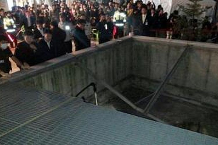 Petugas polisi berkumpul di dekat sebuah lubang ventilasi yang penutupnya ambruk karena diinjak puluhan orang saat menonton sebuah konser musik pop di Korea Selatan.