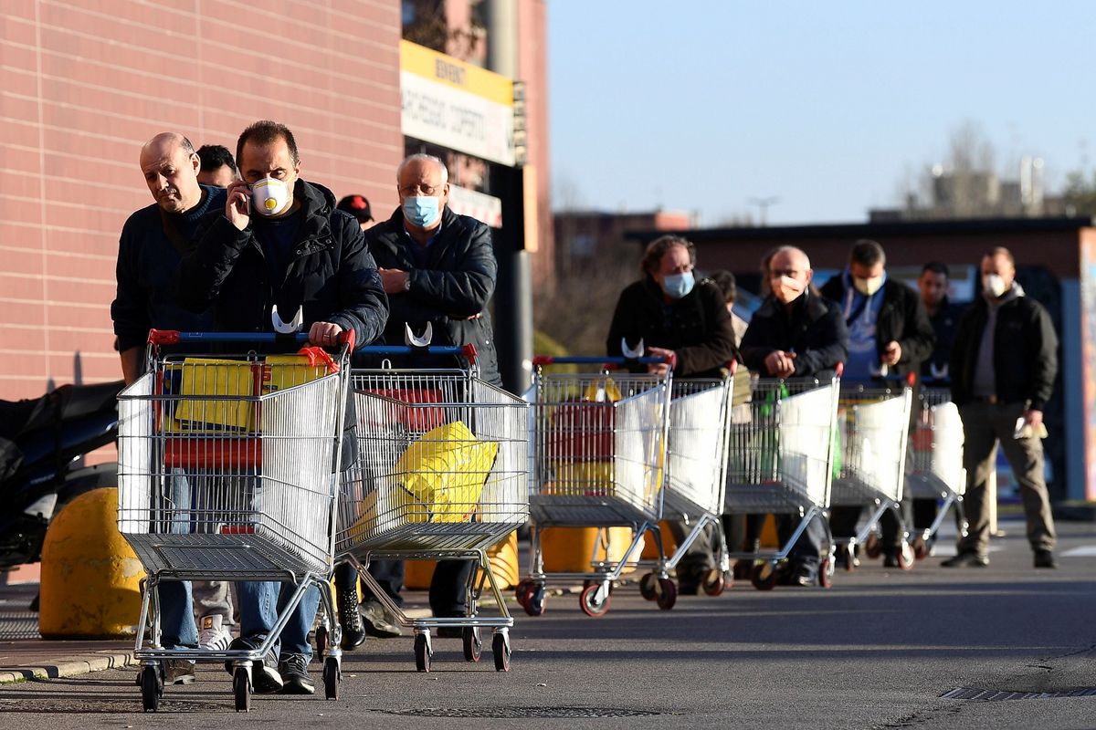 Warga memakai masker mengantre di supermarket pada hari kedua lockdown Italia. Gambar diambil di Pioltello, dekat Milan, Rabu (11/3/2020).