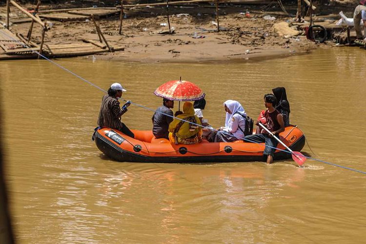 Sejumlah warga melintasi sungai Ciberang menggunakan perahu karet di Kampung Somang, Lebak, Banten, Senin (20/1/2020). Sebanyak 28 jembatan rusak diterjang banjir bandang dan longsor, warga berharap pemerintah segera membangun kembali infrastruktur yang rusak supaya aktivitas serta perekonomian mereka bisa cepat pulih.