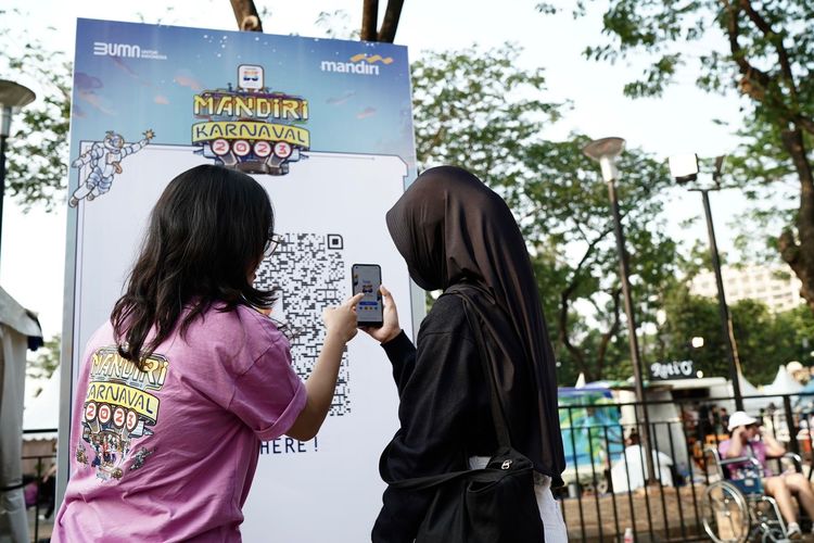 Salah satu pengunjung Mandiri Karnaval 2023 sedang mengunduh Super App Livin? by Mandiri sebagai akses masuk untuk menyaksikan Mandiri Karnaval 2023 di Parkir Timur Kompleks Gelora Bung Karno (GBK), Senayan, Jakarta, Sabtu (7/10/2023) dan Minggu (8/10/2023).
