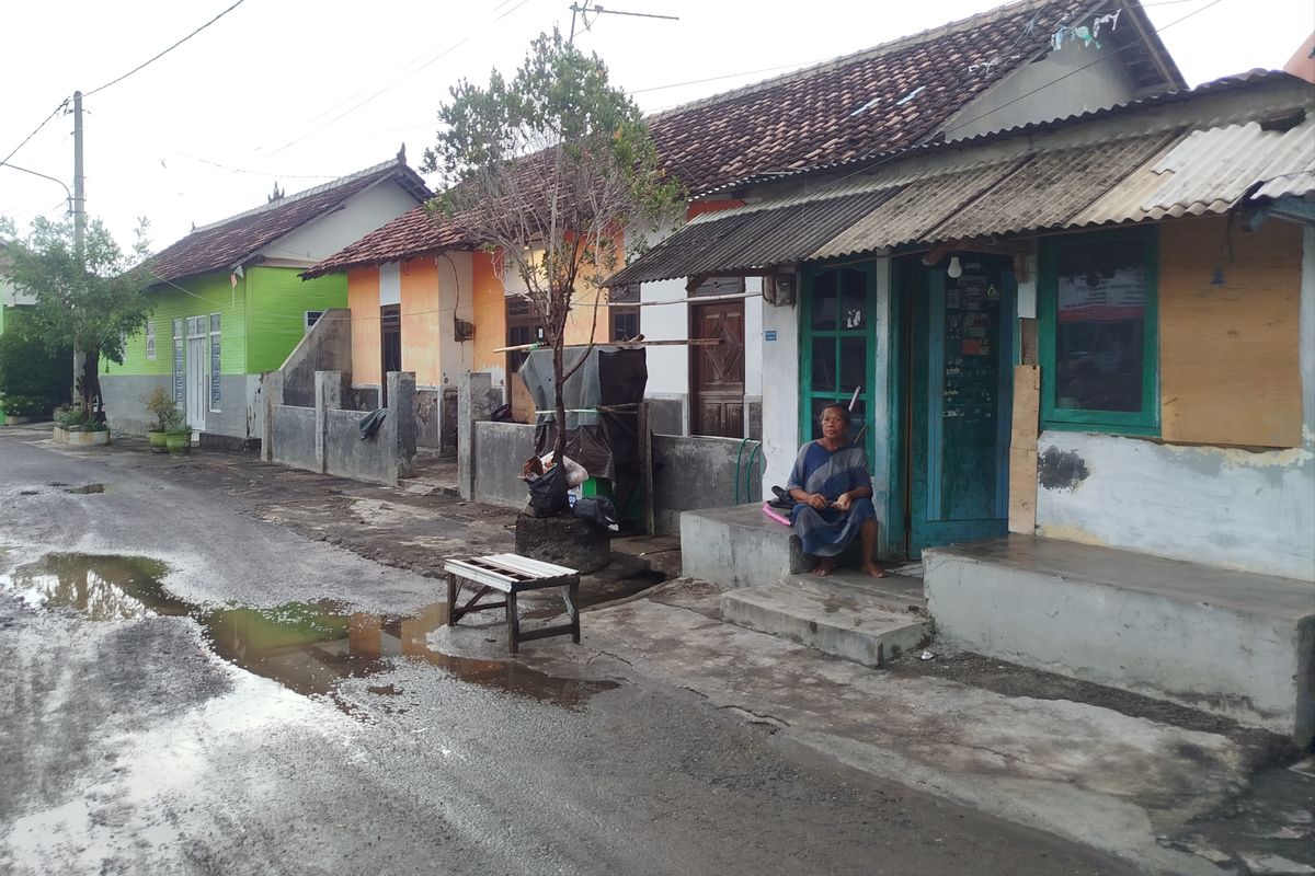 Satinah berada di depan rumahnya sembari mempersiapkan diri jika banjir tiba-tiba melanda. (KOMPAS.COM/Fitri Anggiawati)