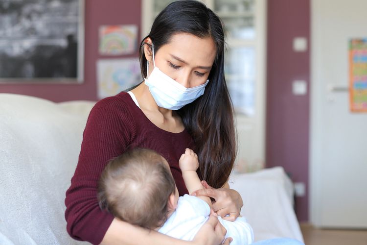 Ilustrasi ibu terkena atau positif Covid-19 menyusui bayi, menggendong bayinya.