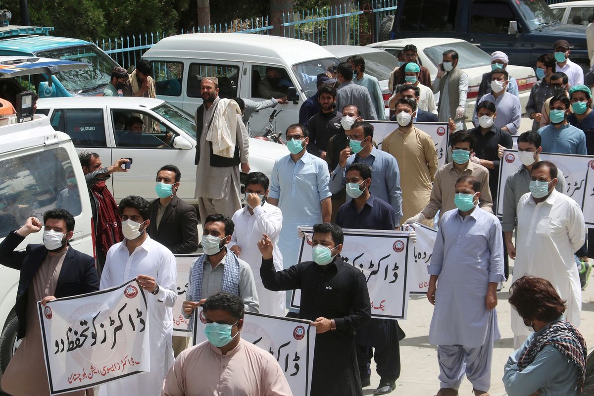 Para dokter memakai masker dan pakaian medis saat melakukan protes kekurangan Alat Pelindung Diri (APD) untuk menangani virus corona di Quetta, Pakistan, Senin (6/4/2020).