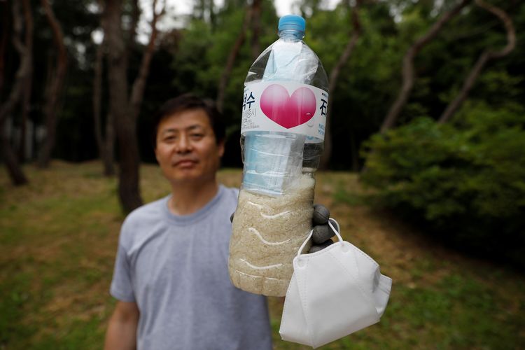 Park Jung-oh, pimpinan kelompok pembelot Korea Utara bernama Kuensaem, berfoto sambil memegang botol plastik berisi beras dan masker yang akan dikirim ke Korut. Foto diambil di Seoul, Korea Selatan, pada 18 Juni 2020.