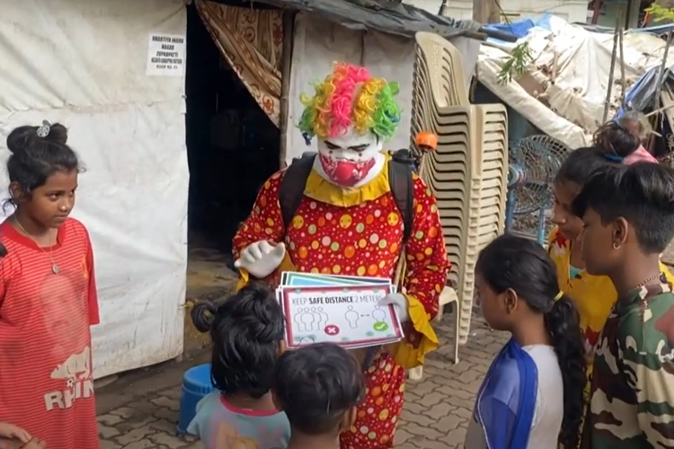 Ashok Kurmi, mengenakan setelan badut merah cerah setiap hari berkeliling daerah kumuh Indiam mendesinfeksi ruang publik, membagikan masker wajah, dan menyebarkan kesadaran tentang Covid-19.
