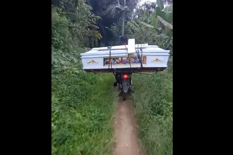 Foto: Tangkapan Layar video dari akun Facebook. Seorang pemotor membawa peti dan salib di Dusun Bulu Malanda, Nagori Parmonangan, Kecamatan Dolok Panribuan, Kabupaten Simalungun.