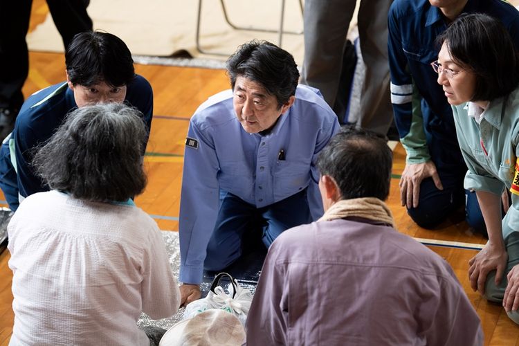 Perdana Menteri Jepang Shinzo Abe saat berbicara dengan beberapa korban terdampak bencana longsor di pusat evakuasi warga di kota Kurashiki, prefektur Okayama, Rabu (11/7/2018).