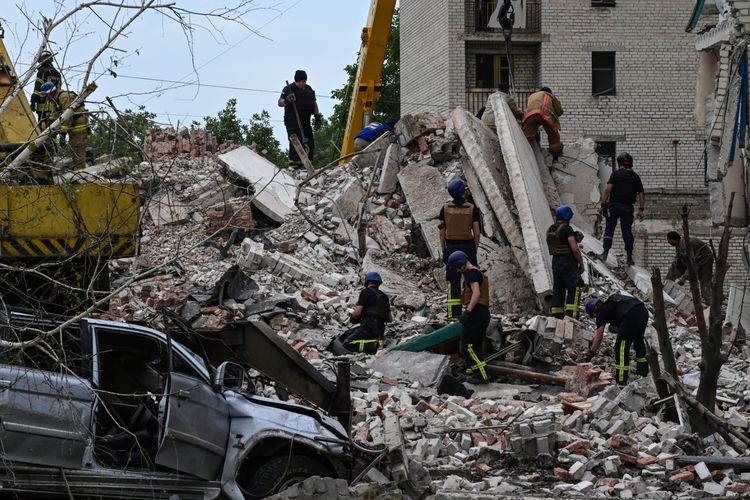 Tim penyelamat membersihkan tempat kejadian setelah sebuah bangunan hancur sebagian akibat serangan rudal Rusia di sebuah bangunan perumahan empat lantai di Chasiv Yar, Distrik Bakhmut, Ukraina timur, pada 10 Juli 2022. Pada Senin (31/10/2022), Ukraian menyebut 50 rudal ditembakkan dari Rusia.