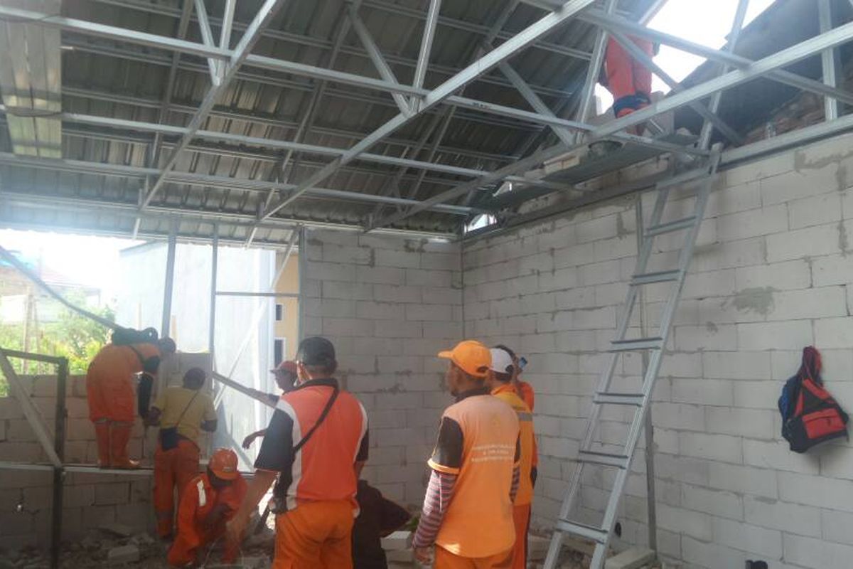 Pasukan merah dan petugas PPSU sedang melakukan pemasangan atap dan tembok di rumah-rumah yang termasuk dalam program bedah rumah yang dicanangkan Pemprov DKI Jakarta, Jumat (5/5/2017)