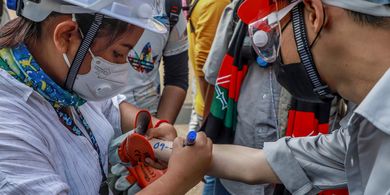 An anti-coup protester writes emergency information of another protester on his arm in Yangon, Myanmar, (3/3/2021)