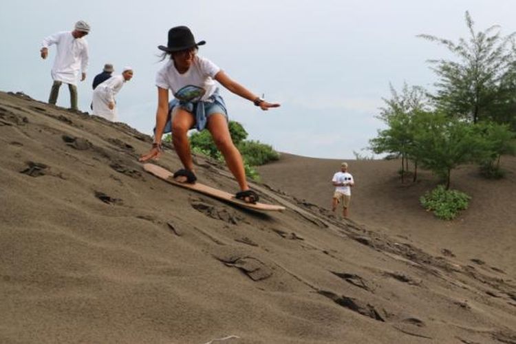 Wisatawan sandboarding di Pantai Parangkusumo, salah satu pantai terkenal di Yogyakarta.