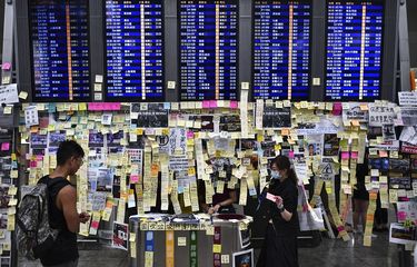 Situasi bandara internasional Hong Kong setelah aksi unjuk rasa di aula kedatangan pada 26 Juli 2019. Tampak sejumlah catatan yang ditempelkan para pengunjuk rasa di dekat papan pengumuman keberangkatan.
