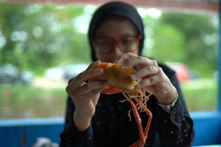 Seorang pengunjung menyantap udang galah besar di RM Upik Banun, Pekanbaru.