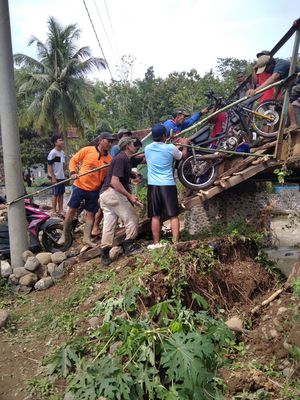 Warga Dusun Bangbayang memindahkan motor mereka menyeberangi Sungai Ciawi untuk di simpan di Kampung Babakan yang ada di seberang sungai agar bisa tetap beraktivitas ke luar dusun, Kamis (23/09/2022)