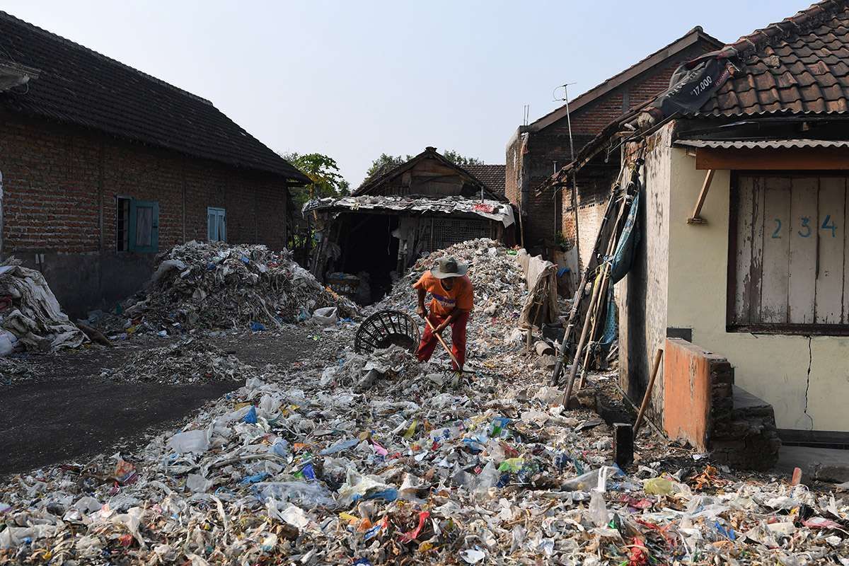 Foto dirilis Selasa (6/8/2019), menunjukkan seorang warga memilah tumpukan sampah plastik impor sekitar rumahnya di Desa Bangun di Mojokerto, Jawa Timur. Indonesia diperkirakan setiap harinya menerima sedikitnya 300 kontainer sampah yang sebagian besar menuju ke Jawa Timur, diduga dampak kebijakan China yang menghentikan impor sampah plastik dari sejumlah negara di Uni Eropa dan Amerika.