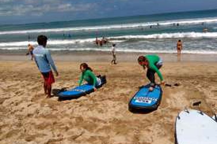Turis Jepang sedang belajar surfing di Pantai Kuta, Bali.