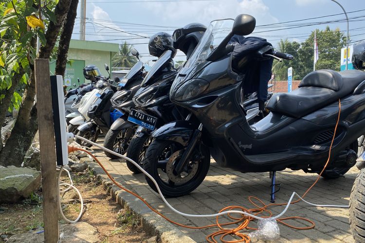 Rombongan pengguna motor listrik melakukan pengisian daya dengan charger bawaan di pos SPKLU PLN