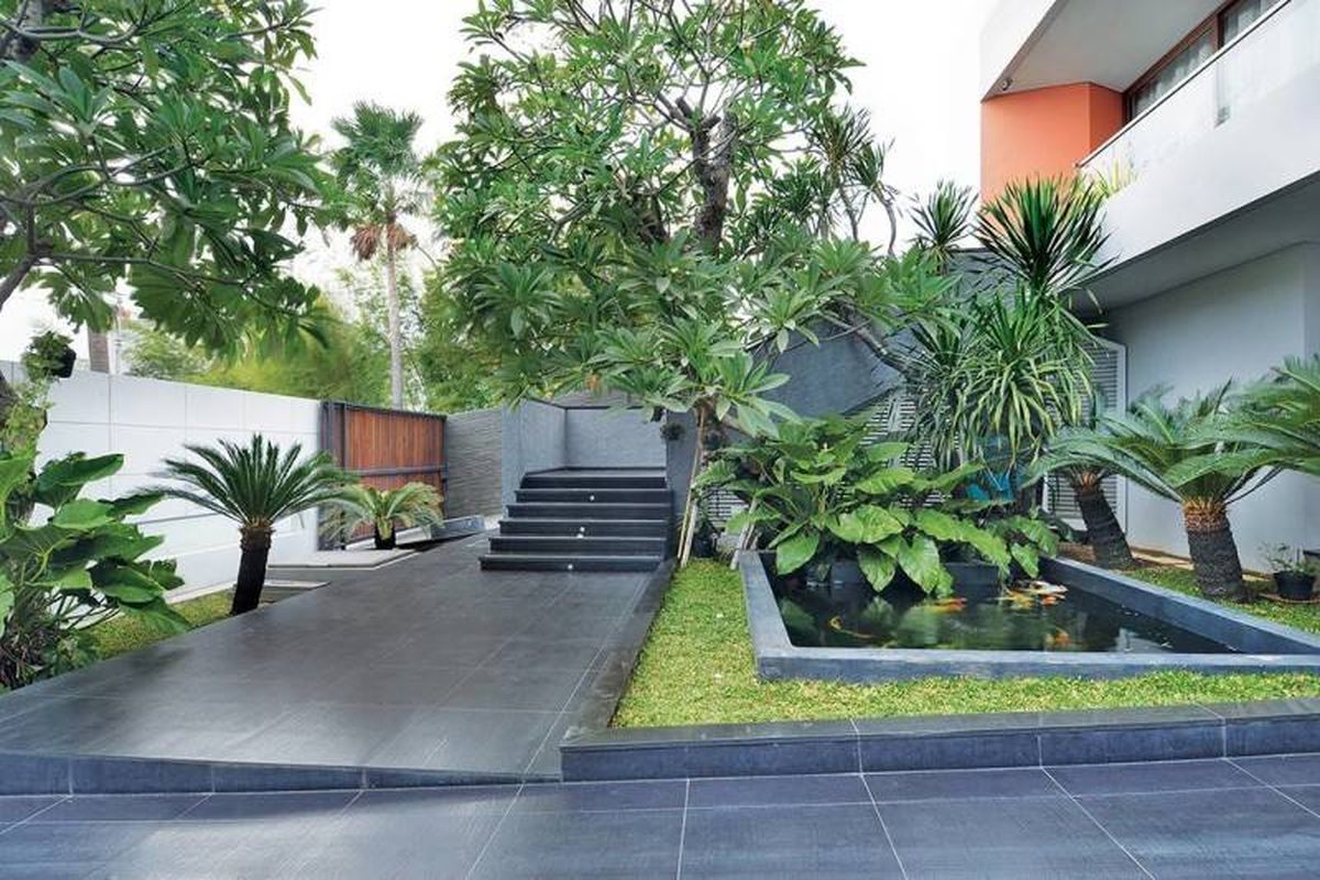 Taman di depan rumah Green Garden House karya Denny Setiawan dengan kolam ikan koi dan tanaman tropis yang menyejukkan.