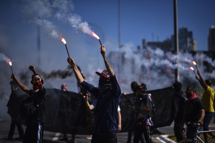 Pengunjuk rasa menyalakan suar dalam aksi protes menentang rasisme, kebijakan Presiden Jair Bolsonaro, dan mempertahankan demokrasi di tengah wabah virus corona di Brasil, pada 21 Juni 2020.