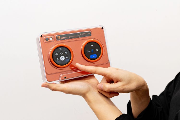 Penampakan AI OLED Cassette, perangkat konsep yang terinspirasi dari pemutar kaset klasik. Meski bentuknya menyerupai kaset tape, perangkat ini dibekali dua layar OLED bulat berukuran 1,5 inci.