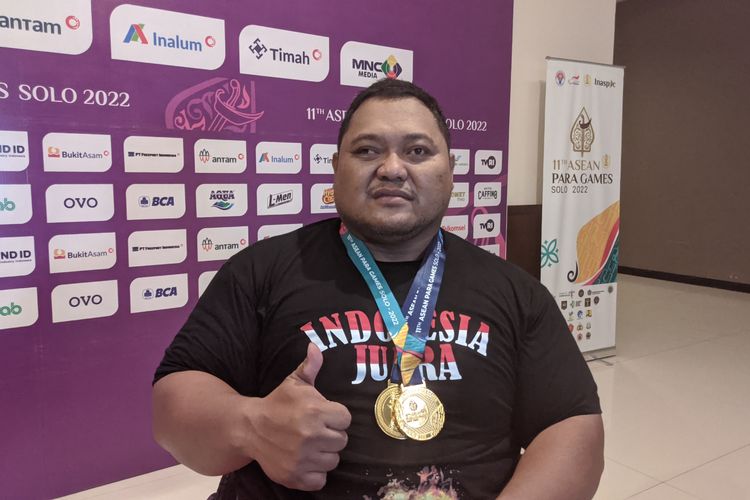 Atlet powerlifting Indonesia, Atmaji Priambodo, berpose dengan medali emas ASEAN Para Games 2022 yang ia dapatkan usai menjuarai kelas 80 kg putra pada laga yang digelar di Hotel Solo Paragon, Jumat (5/8/2022).