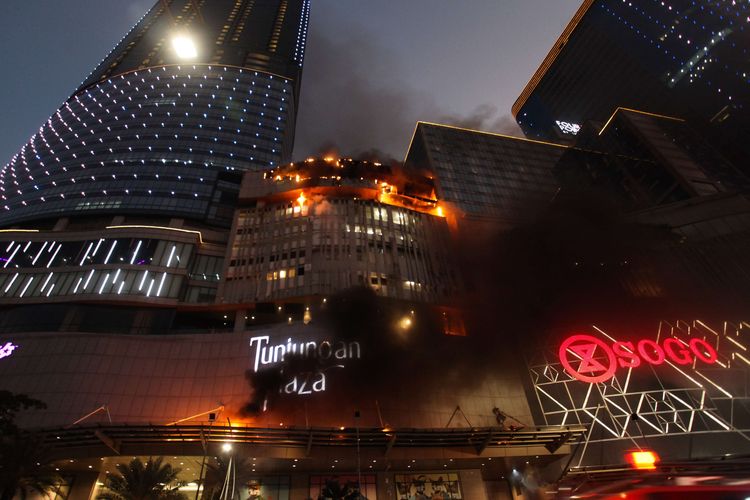 Kobaran api muncul dari Tunjungan Plaza 5 yang terbakar di Surabaya, Jawa Timur, Rabu (13/4/2022). Sejumlah kendaraan pemadam kebakaran dikerahkan termasuk tiga Bronto Skylift untuk memadamkan api yang membakar lantai 5 Tunjungan Plaza 5 itu.