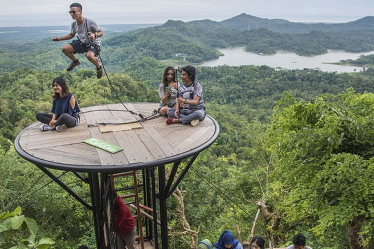 Wisatawan menunggu giliran berfoto dengan latar belakang pemandangan Waduk Sermo di obyek wisata Kalibiru, Desa Hargowilis, Kecamatan Kokap, Kulon Progo, DI Yogyakarta, Jumat (2/12/2016). Obyek wisata itu dikembangkan dan dikelola warga setempat sehingga mampu menjadi sumber pendapatan bagi masyarakat di kawasan itu. 