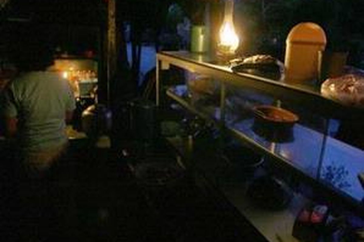 Akibat pemadaman di beberapa kawasan di DKI Jakarta karena berkurangnya pasokan listrik Jawa-Bali, sebagian warga dan pedagang warung nasi sederhana di daerah Simprug, Jakarta Selatan, Jumat (24/11), menggunakan penerangan seadanya.