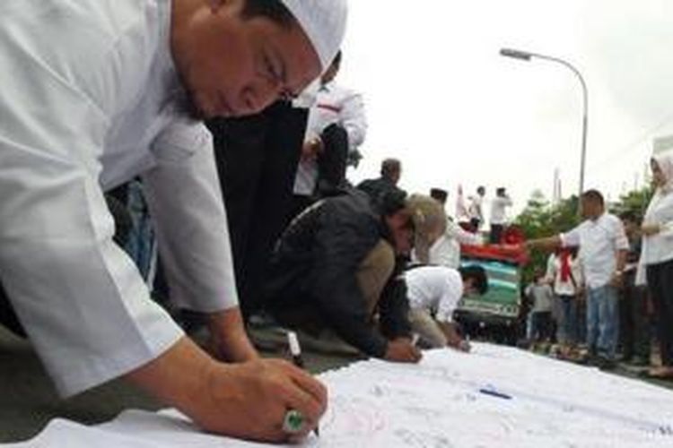 Simpatisan Prabowo-Hatta membubuhkan tanda tangan di atas spanduk putih saat berunjuk rasa di depan Gedung Mahkamah Konstitusi (MK), Jakarta, Jumat (25/7/2014). Prabowo-Hatta mendaftarkan gugatan ke MK atas hasil pemilu presiden.