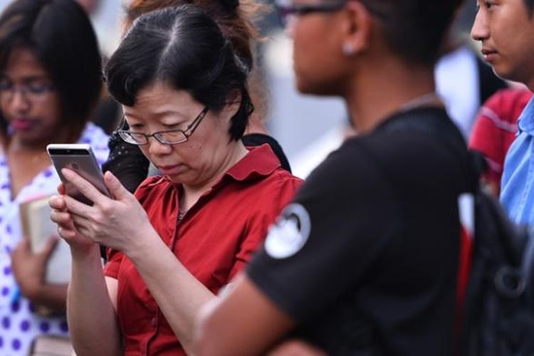 Konsul Jenderal China di Kota Kinabalu, Sabah, Chen Peije (baju merah) sedang melihat ke telepon genggamnya sembari menanti kabar soal 28 turis China yang hilang di perairan Sabah.