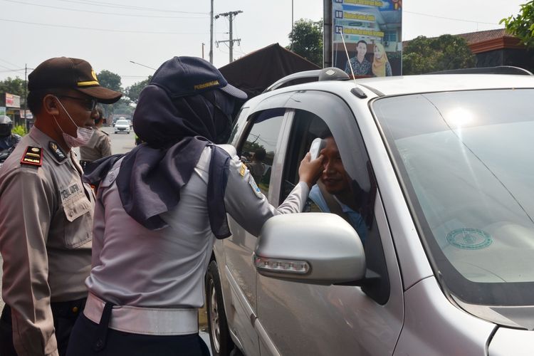 Petugas gabungan mengecek suhu tubuh pengguna jalan di perbatasan Di Kecamatan Sokaraja, Kabupaten Banyumas, Jawa Tengah, Kamis (19/3/2020).