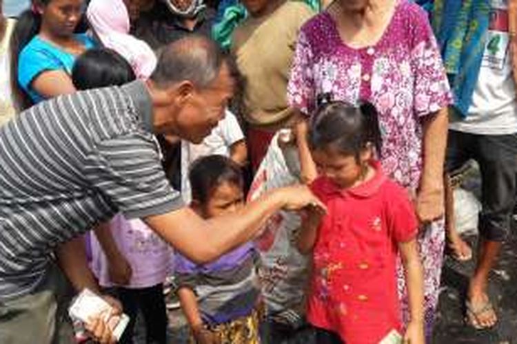 Bripka Seladi, Anggota Satlantas Polres Malang Kota yang dikenal sebagai polisi jujur saat memberikan uang kepada salah satu anak pemulung di TPA Lowok Doro, Kota Malang, Jawa Timur, Minggu (7/8/2016)