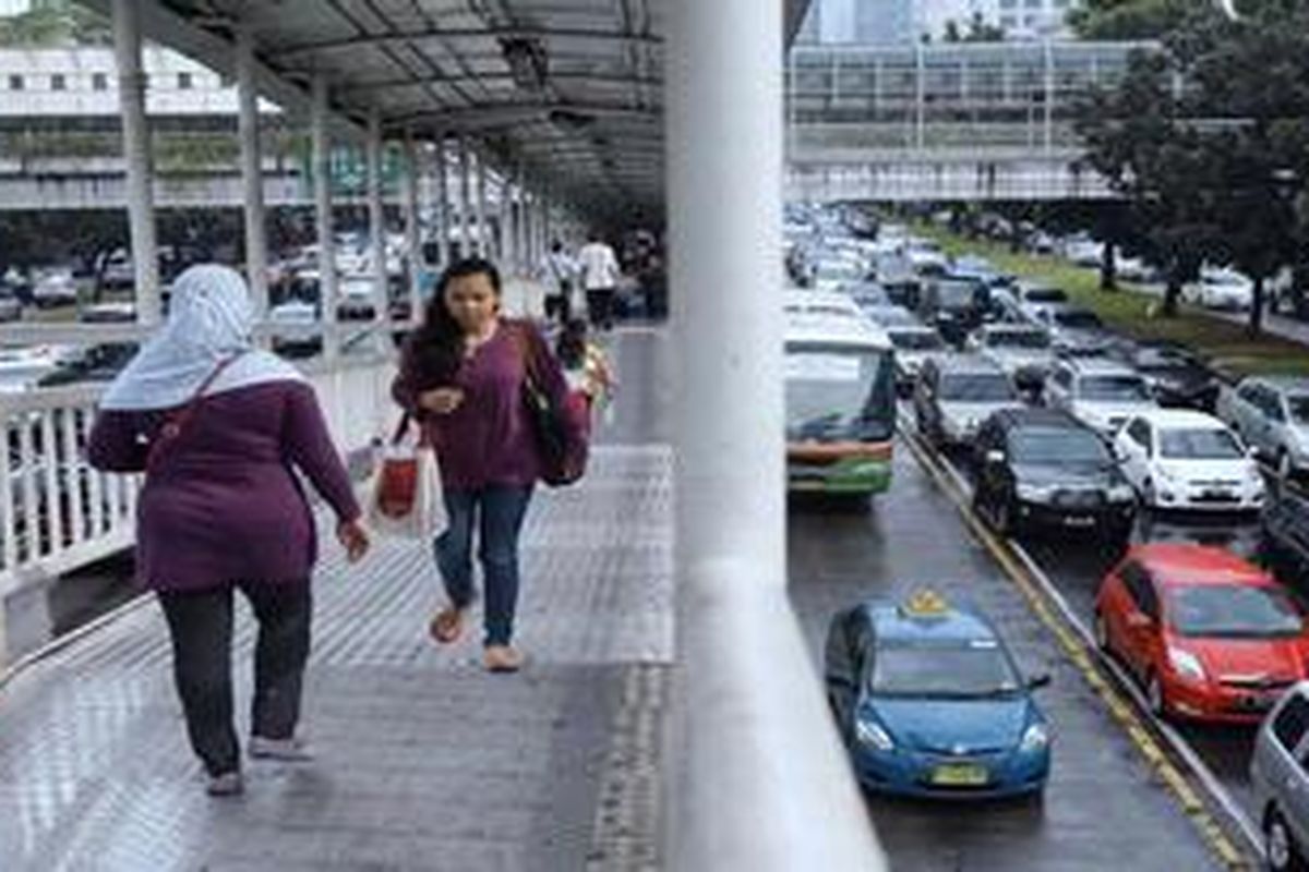 Penumpang berjalan di jembatan penyeberangan usai sampai di Halte Dukuh Atas, Jakarta Selatan, Kamis (11/4/2013). Pembenahan sarana angkutan umum mendesak dilakukan untuk mencegah lalu lintas Jakarta macet total.