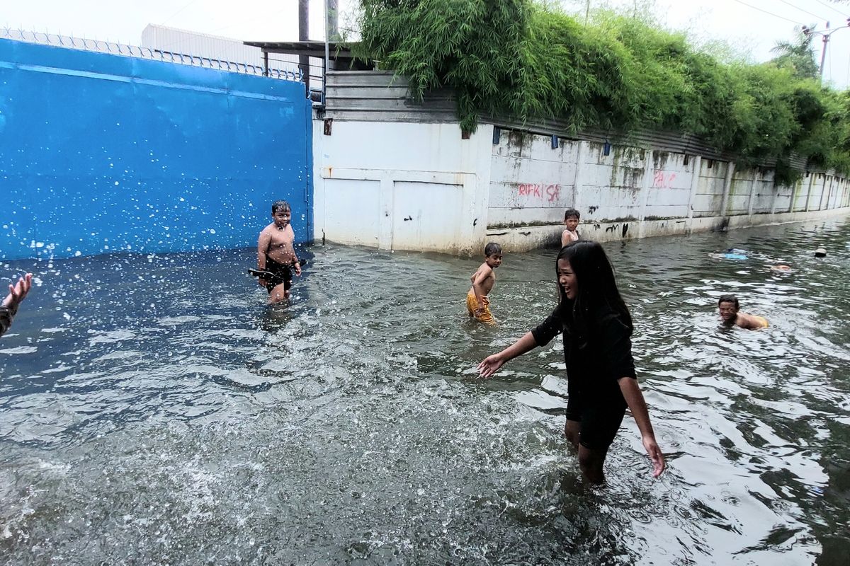 Bocah di RW 011 Tegal Alur bermain air dan berenang di titik banjir luapan Kali Semongol, Tegal Alur, Kalideres, Jakarta Barat, pada Kamis (20/1/2022) siang.