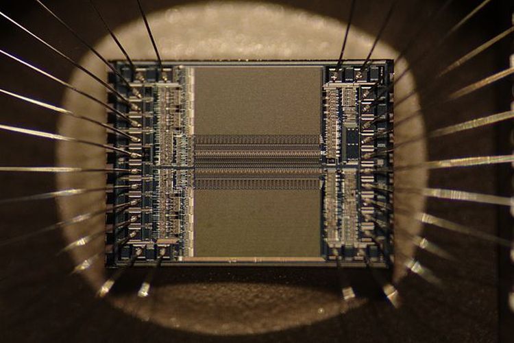 microchip EPROM menunjukkan detail sirkuit terintegrasi itu sendiri dan kabel perak yang menghubungkan die ke kaki chip. Gambar mencakup area sekitar 5 kali 4 mm.