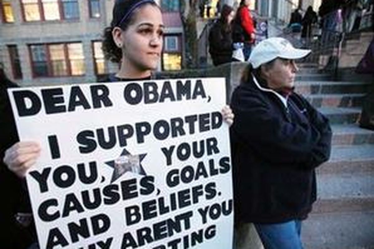 In this Tuesday, March 9, 2010 photo, former student Ashley Delgado, left, stands with a sign next to Joe Clavin outside Central Falls high school in Central Falls, R.I. Instructors and staff will be fired after the end of the school year in a desperate move to improve student performance at the school. The firings were provoked by dismal student performance: In 2009, fewer than half of its students graduated within four years. And standardized tests last fall showed just 7 percent of eleventh graders passing math, 33 percent passing writing and 55 percent proficient in reading. The school educates just over 1,000 students. 