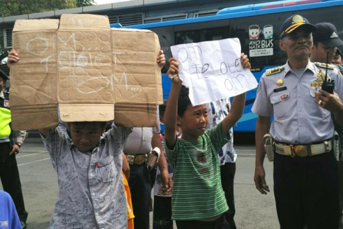 Anak-anak menunjukkan kertas dan kardus bertuliskan om telolet om kepada pengemudi bus di Terminal Kalideres, Jakarta Barat, Jumat (23/12/2016).