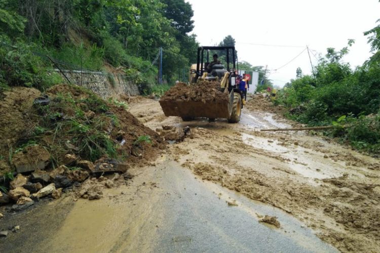 Alat berat berupa loader membersihkan tanah longsor di Desa Sumber Waru Kecamatan Waru Kabupaten Pamekasan, yang menutup akses jalan dua arah dari Kecamatan Pakong ke Kecamatan Waru pada Sabtu (20/11/2021).