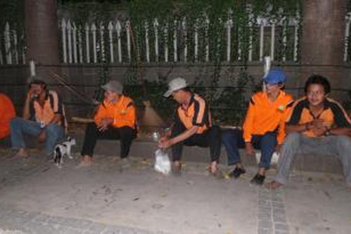 Para pekerja kebersihan di Bundaran HI, Jakarta menunggu saat untuk membersihkan sampah. Salah satunya yakni Edi (43), yang tak dapat melakukan Takbiran bersama keluarga di rumah. Kamis (16/7/2015) 
