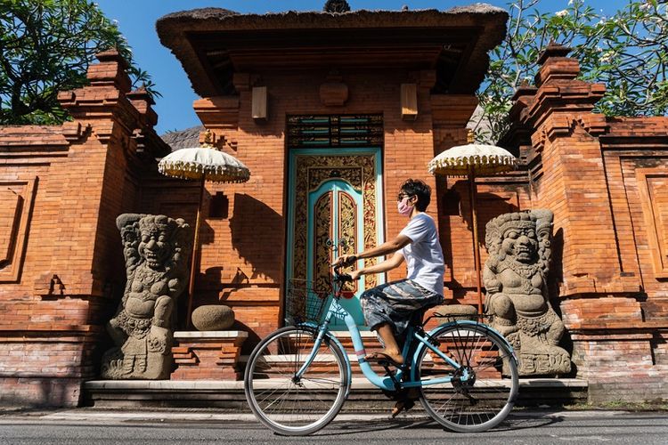Ilustrasi wisatawan bersepeda sambil memakai masker di Bali 
