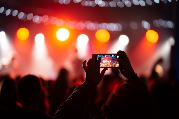 Ilustrasi penonton konser menggunakan smartphone.