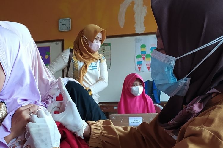 Jihana (9) siswi kelas 3 MI Maarif Margasana menangis ketika divaksin Covid-19 di SD Negeri 2 Karanganyar, Kecamatan Jatilawang, Kabupaten Banyumas, Jawa Tengah, Senin (27/12/2021).