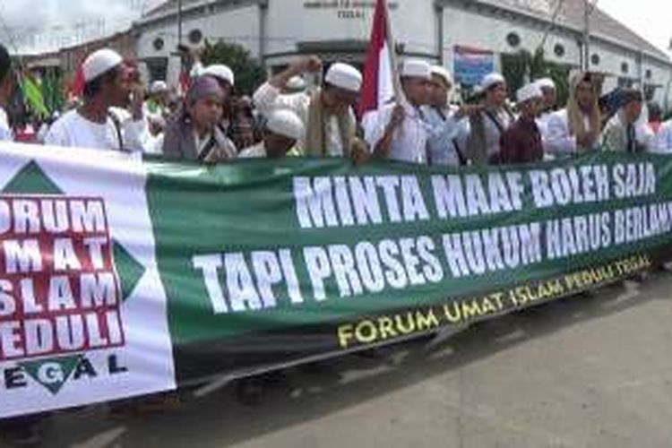 Massa yang tergabung dalam Forum Umat Islam Peduli Tegal, Jawa Tengah, embentangkan spanduk saat berunjuk rasa menuntut agar Ahok diadili karena pernyataannya.