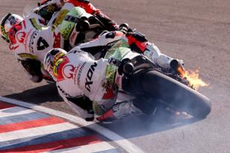 Motor pebalap Pramac Racing asal Kolombia, Yonny Hernandez (belakang), terbakar saat melintasi Sirkuit Termas de Rio Hondo pada balapan GP Argentina, Minggu (19/4/2015).