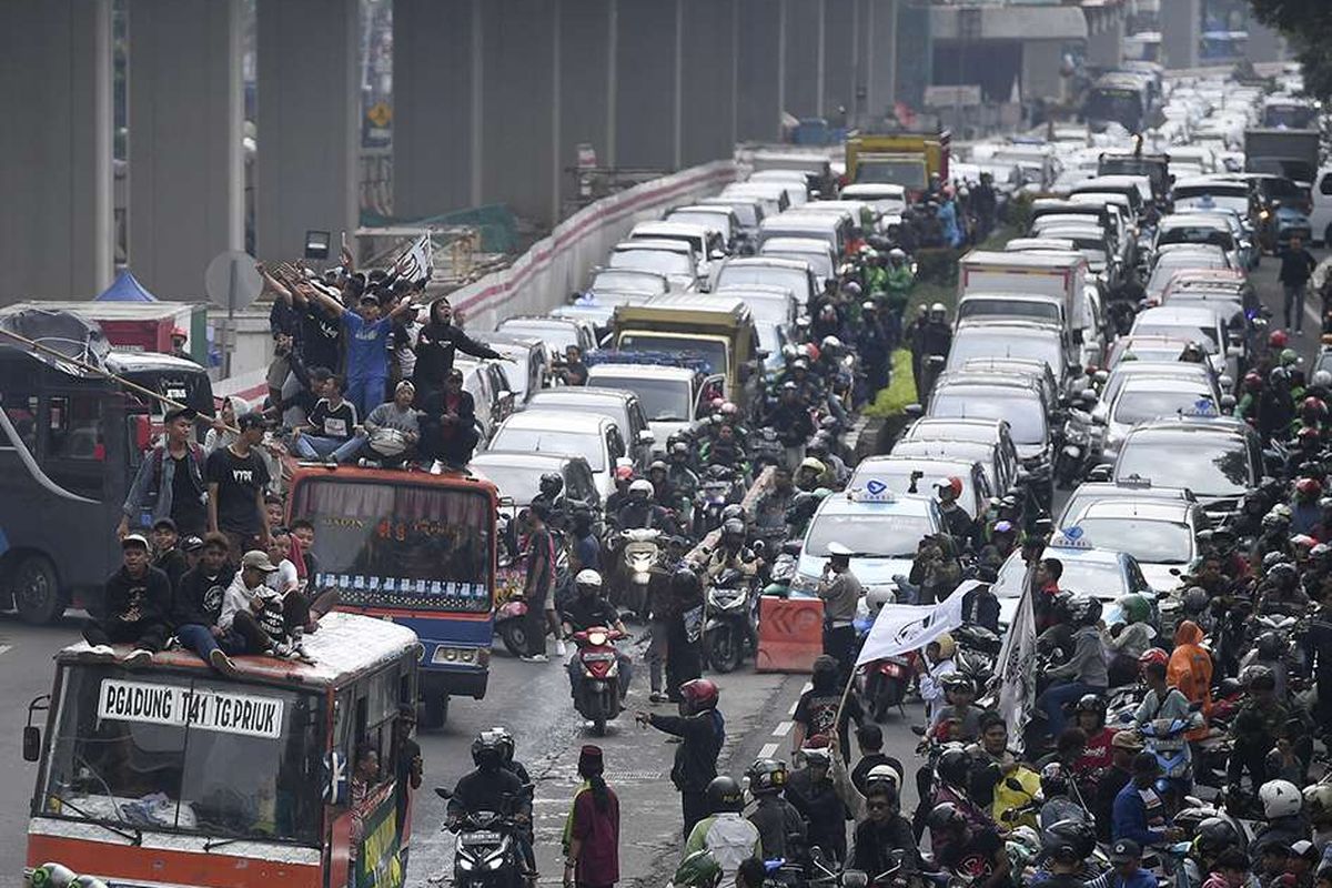 Warga Tanjung Priok menaiki atap metromini saat melakukan aksi di depan gedung Kemenkumham, Jakarta, Rabu (22/1/2020). Ratusan warga Tanjung Priok menuntut Menkumham Yasonna Laoly minta maaf soal ucapan yang menyebut Tanjung Priok merupakan wilayah yang sarat akan tindak kriminal.