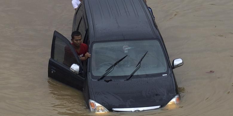 Luapan Kali Ciliwung memutus jalur kendaraan di Jalan KH Abdullah Syafi'ie, Tebet, Jakarta Selatan, Senin (13/1/2014). Luapan kali mulai menggenangi permukiman dan memutus jalan sejak Senin dini hari. KOMPAS/AGUS SUSANTO