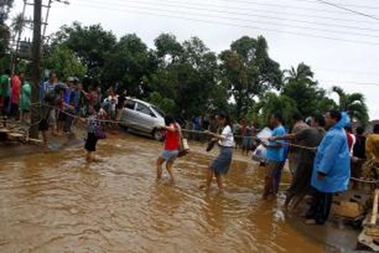 Ruas jalan Trans Sulawesi yang berada di Desa Tateli, Kecamatan Mandolang, Minahasa berubah menjadi sungai kecil akibat diterjang banjir bandang, Rabu (15/1/2014) kemarin.