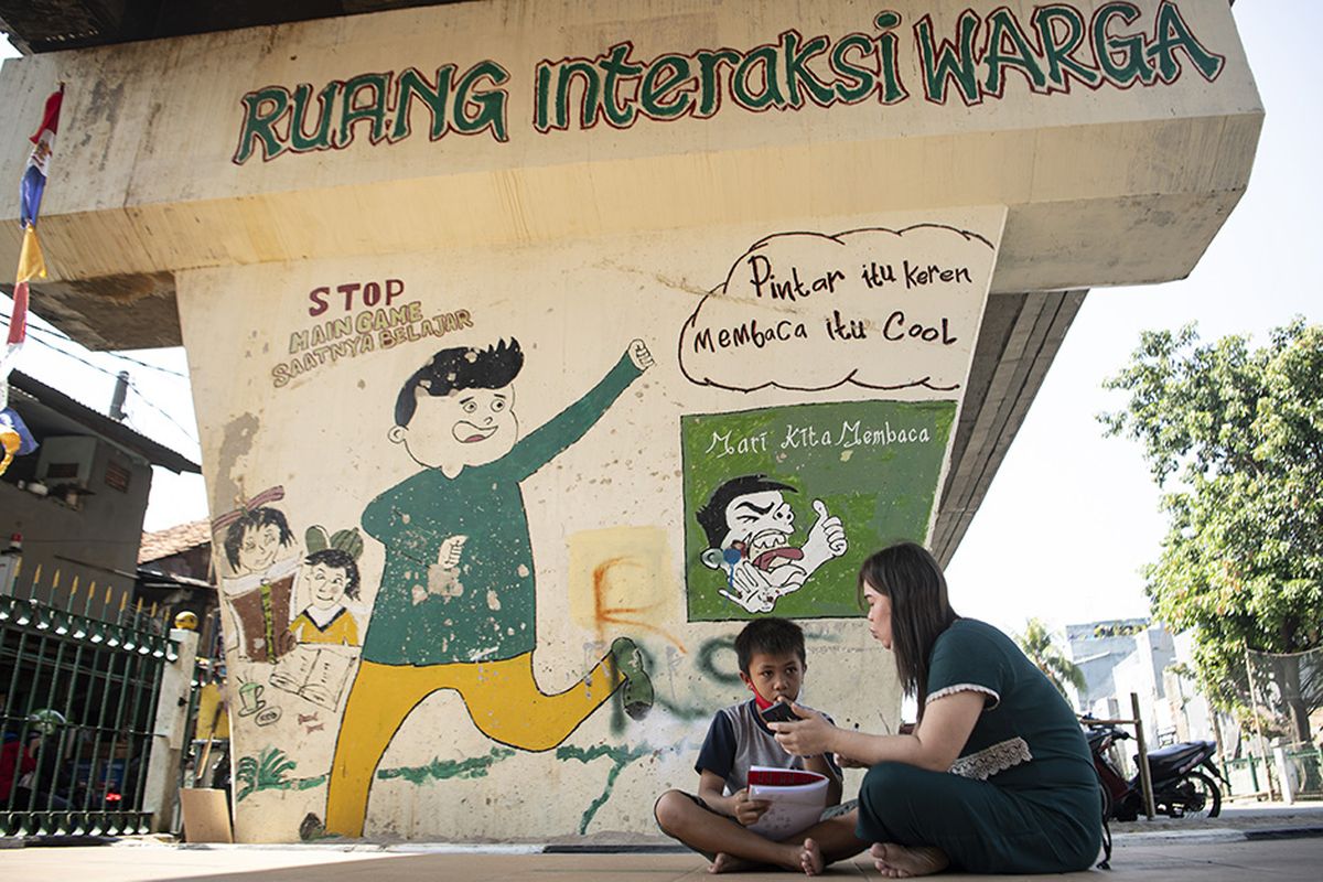 Orang tua siswa membimbing anaknya belajar daring memanfaatkan jaringan internet gratis di kolong rel kereta api Mangga Besar, Jakarta, Rabu (26/8/2020). Fasilitas internet gratis menggunakan modem WiFi yang disediakan oleh warga setempat yang lebih mampu itu bertujuan untuk membantu kelancaran proses belajar daring siswa yang tidak mampu membeli paket kuota internet selama pandemi COVID-19.