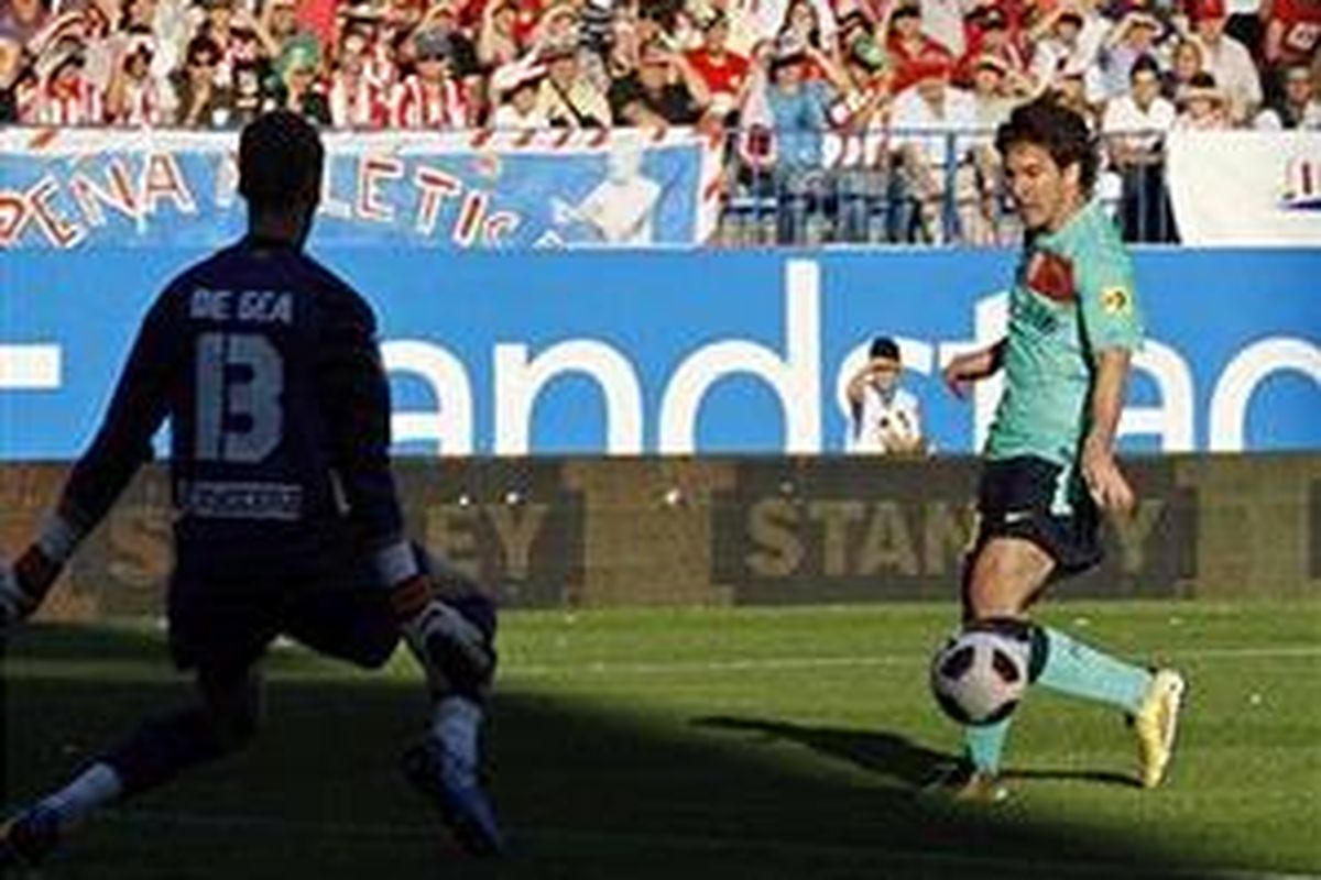 Penyerang Barcelona, Lionel Messi (kanan), menyontek bola masuk ke gawang Atletico Madrid, dalam lanjutan Divisi Primera, Minggu (19/9/2010).