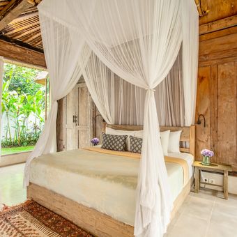Ilustrasi tempat tidur dengan kelambu tulle untuk menghadirkan nuansa kayaknya villa di Bali. 